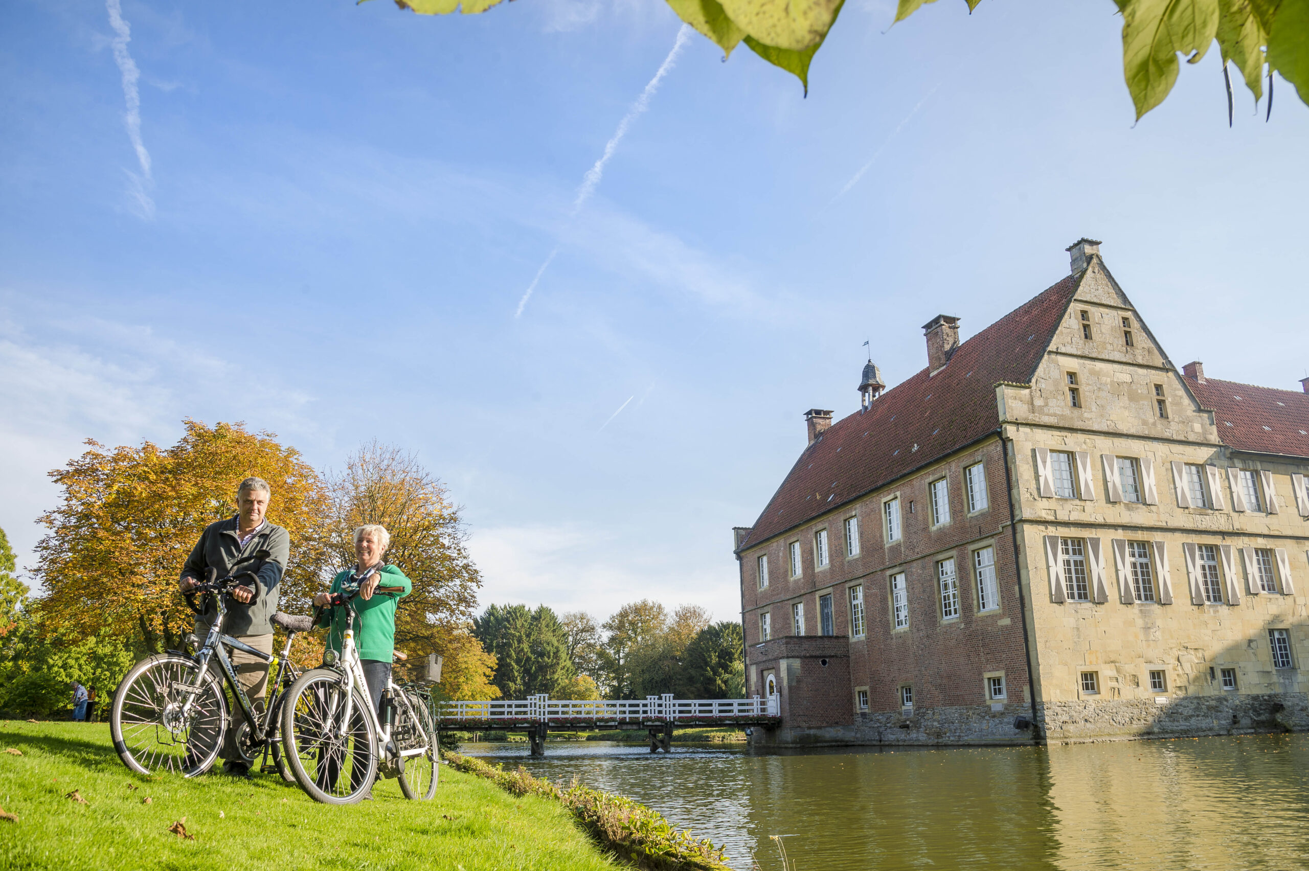 Das Münsterland bietet die schönsten Schlösser und Burgen für einen Kurzurlaub auf dem Rad. Fahrradfahrer an der Burg Hülshoff